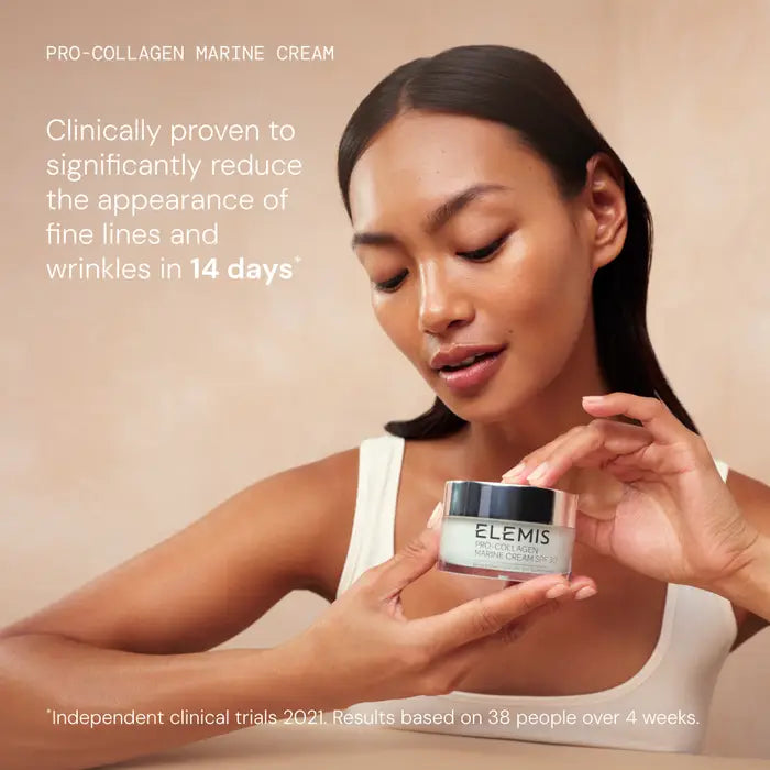 Woman holding a jar of Elemis Pro-Collagen Marine Cream against a beige background.