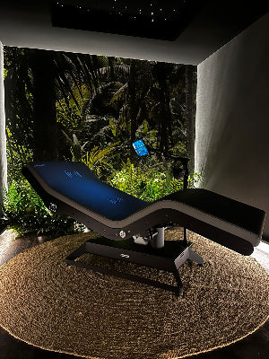 Modern spa bed in a dimly lit room with a tropical outdoor view.