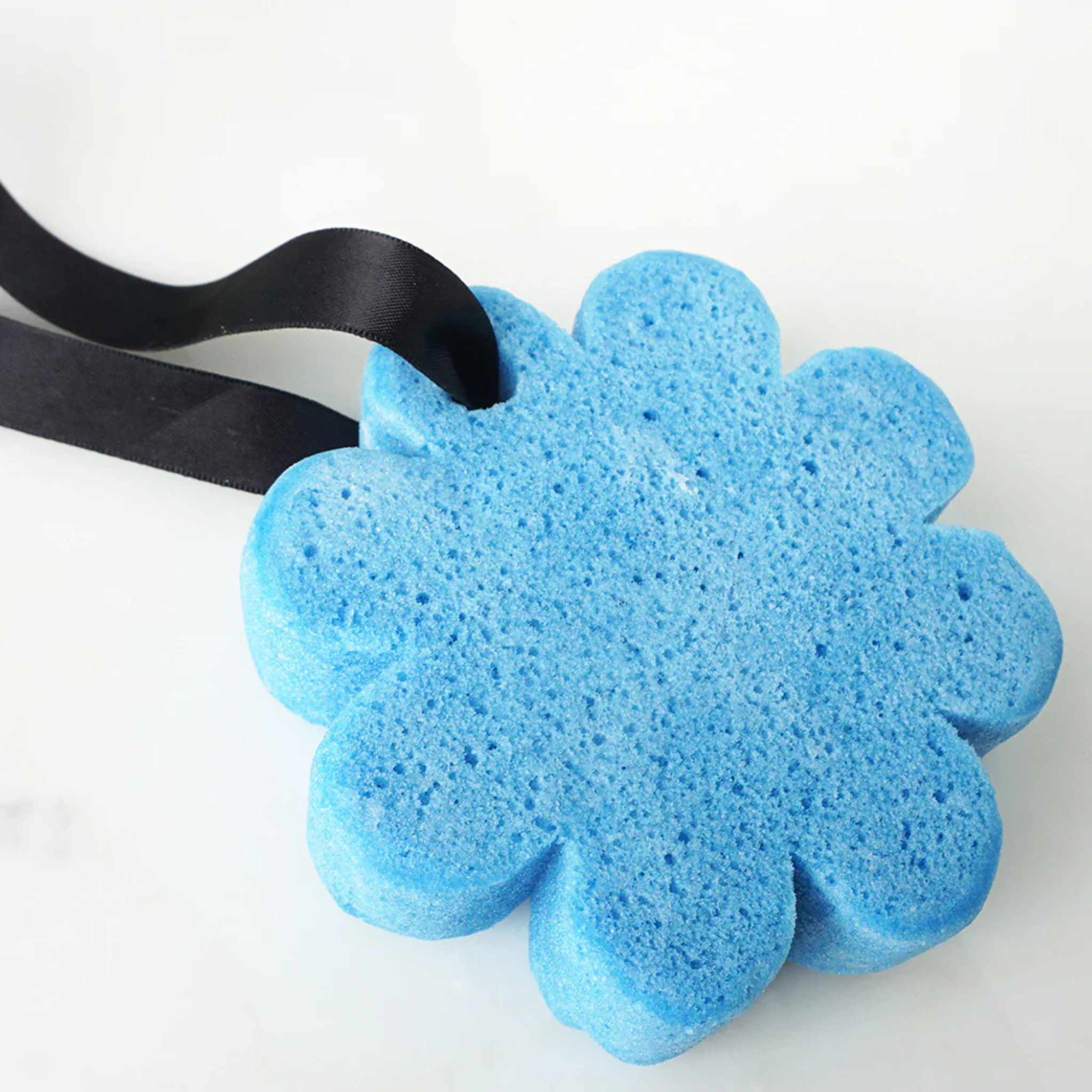 A blue flower shaped sponge on a white surface