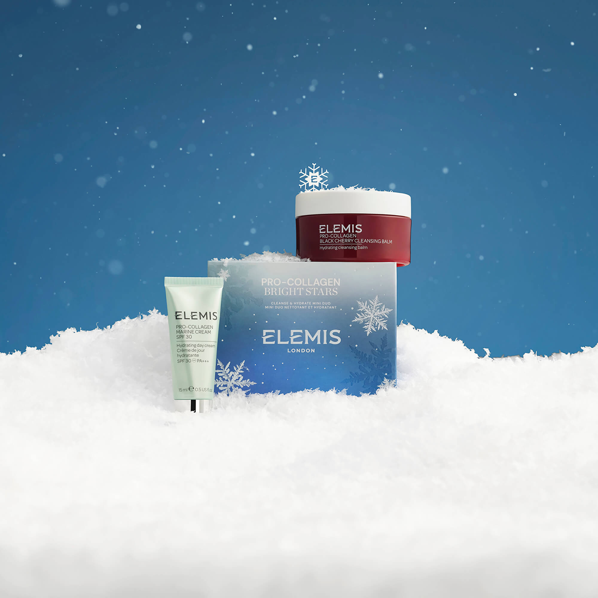 Elemis skincare products in the snow with a blue sky background