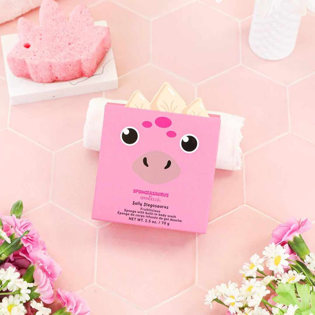 Pink dinosaur shaped sponge with box on top of pink tiled floor