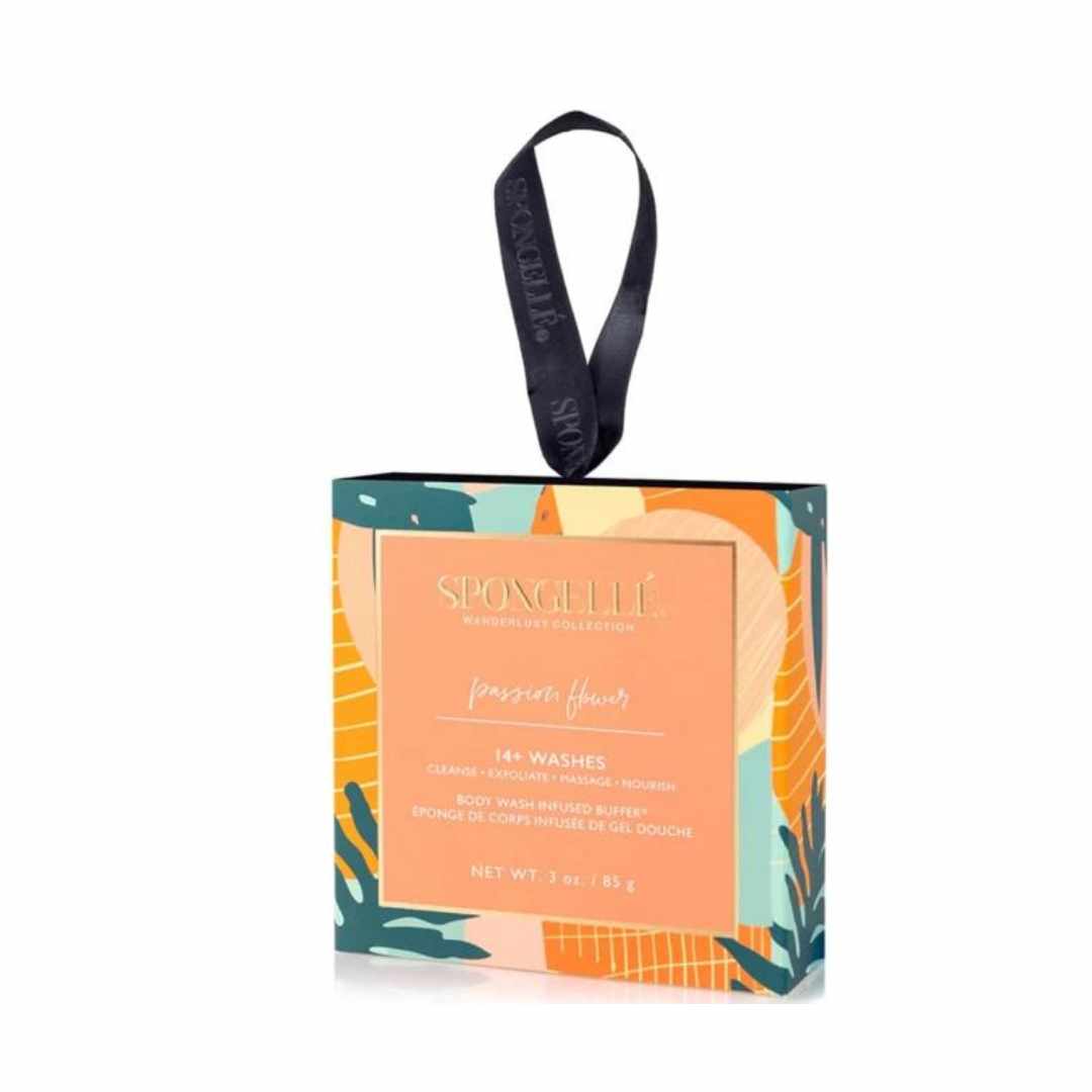 A Spongellé body wash infused buffer in a box with a vibrant, multicolored design featuring floral and tropical elements, and a black tie for hanging.