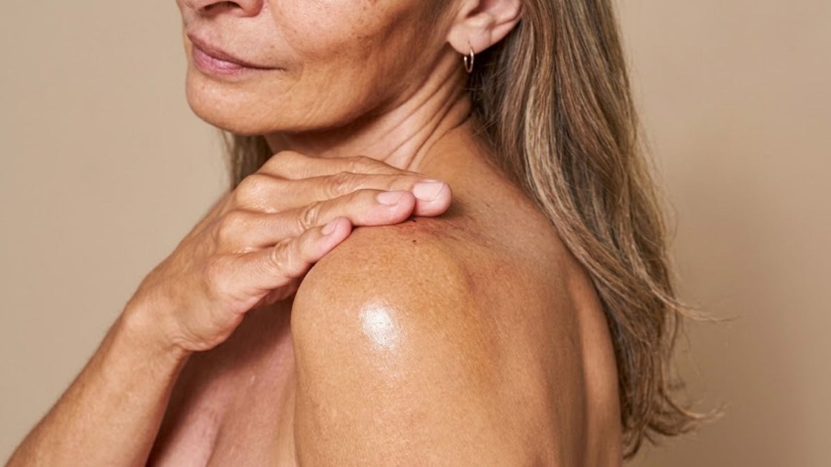 A nude woman touching her shoulder