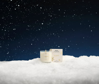 Candle and packaging on a snowy landscape with a dark blue sky.