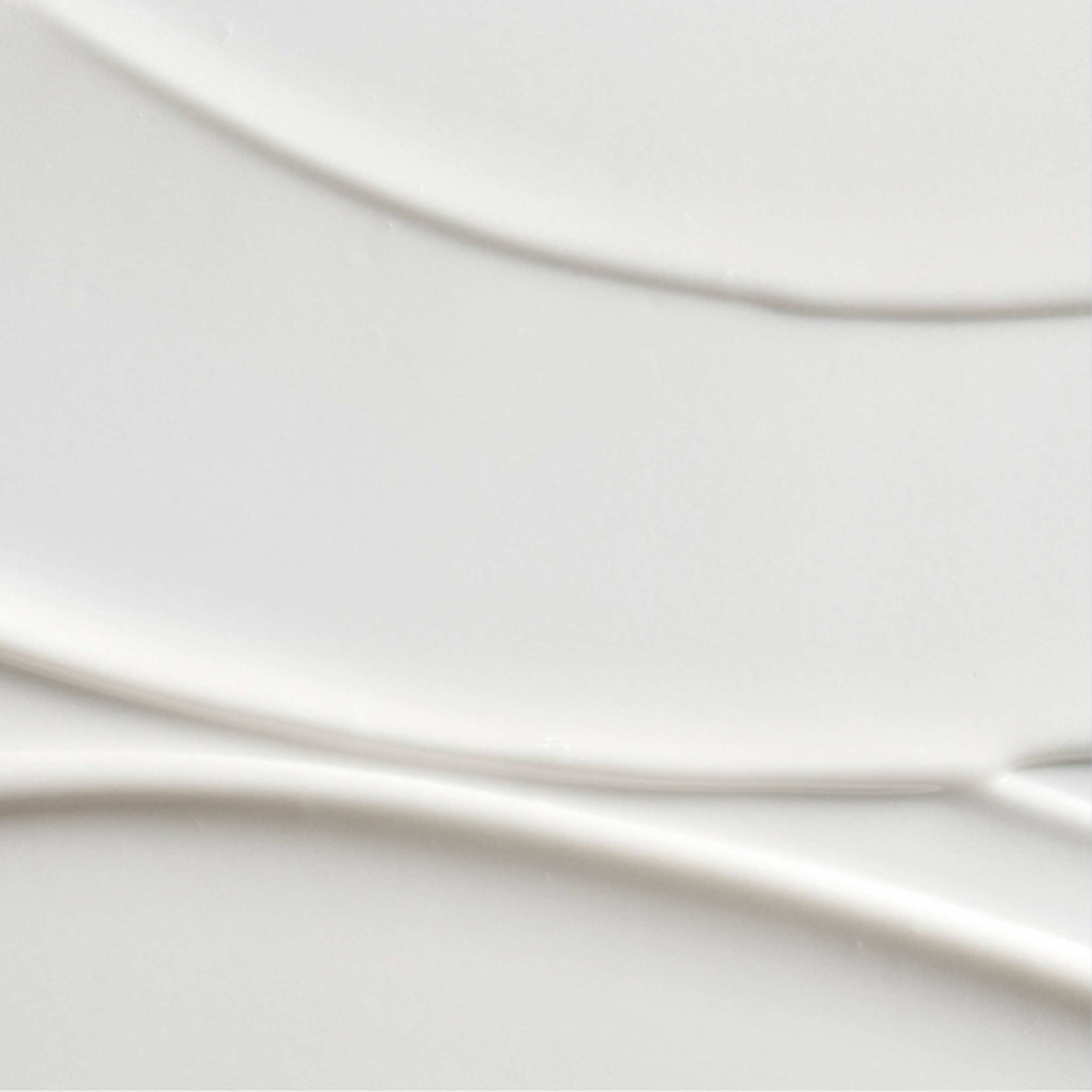 A close-up of a smooth, glossy white ceramic surface with subtle curved lines and soft shadows.