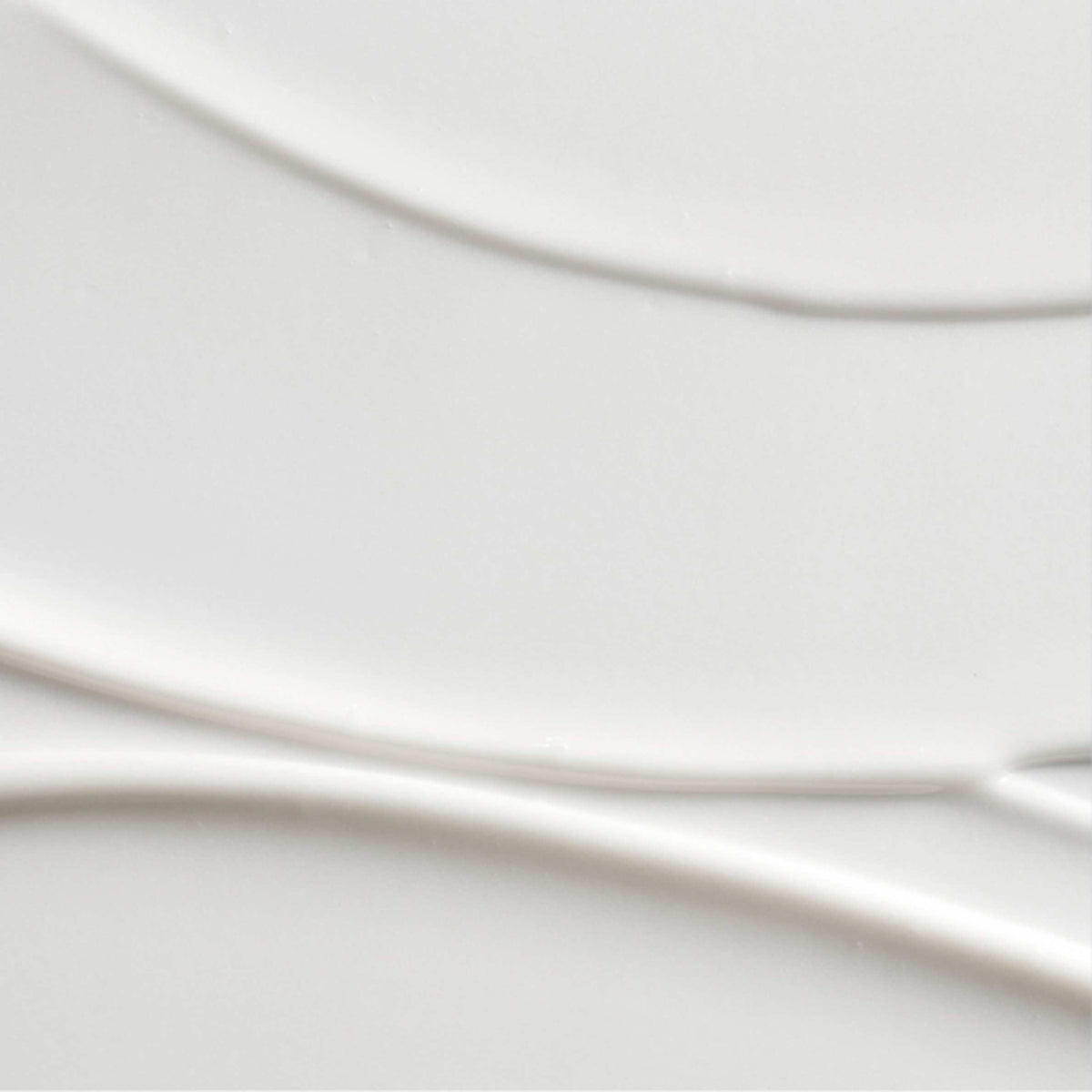 A close-up of a smooth, glossy white ceramic surface with subtle curved lines and soft shadows.