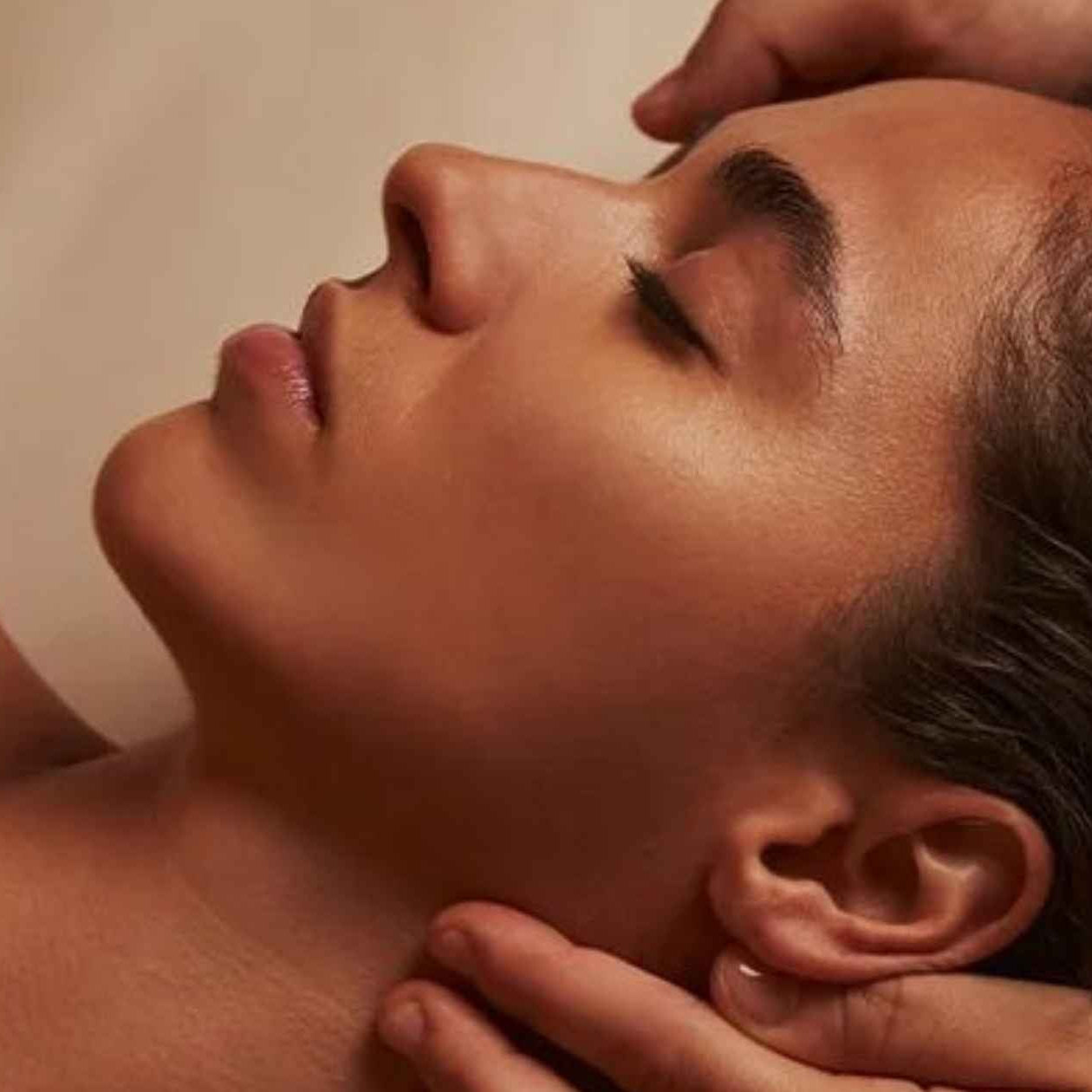 Person receiving a head massage with a neutral background