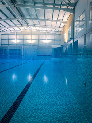 Indoor swimming pool with clear blue water and tiled walls.