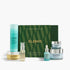 A set of ELEMIS skincare products arranged in front of a dark green patterned box. The set includes a turquoise cleanser bottle, a gold-toned serum bottle, a small turquoise dropper bottle, a light blue serum bottle, and two light blue cream jars with silver lids.